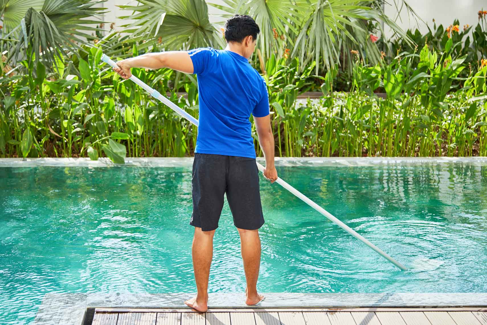 A technician cleaning a swimming pool